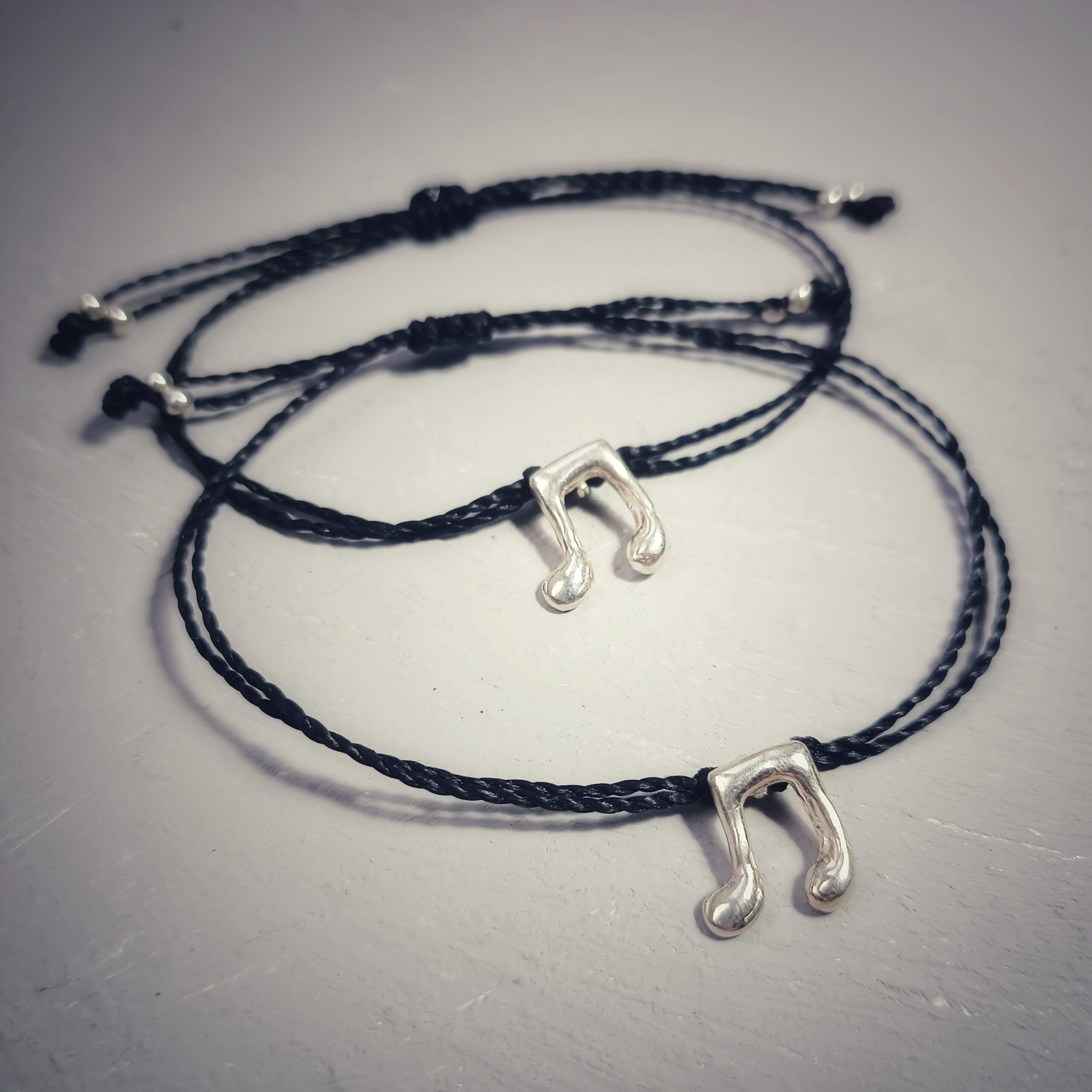 PULSERA NOTAS EN PLATA 925 CON CORDÓN NEGRO CERADO